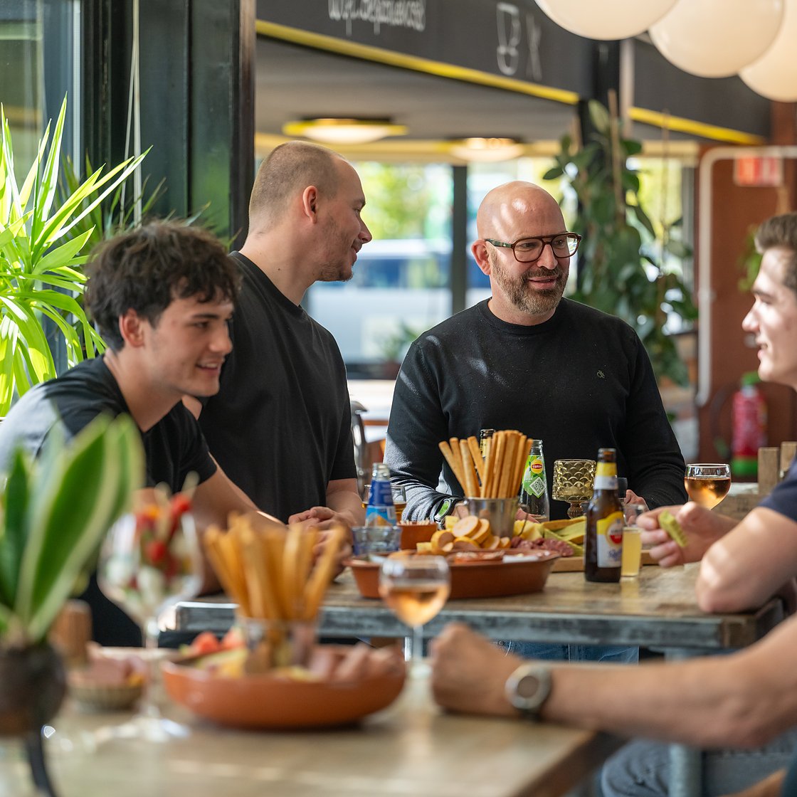 een gezelschap aan tafel met de borrelplanken