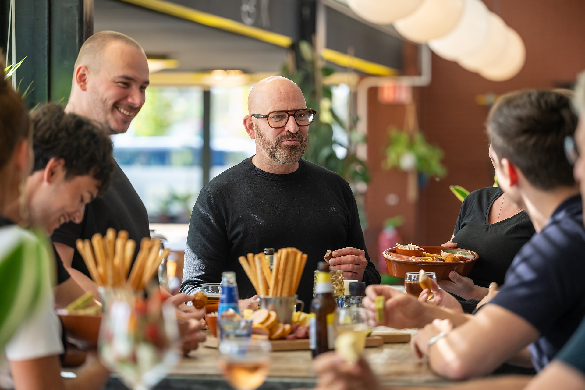 een gezelschap aan de lange tafel met borrelplanken